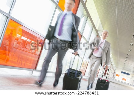 Middle aged businessmen with luggage rushing on railroad platform