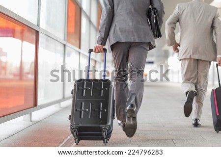 Rear view of businessmen with luggage running on railroad platform