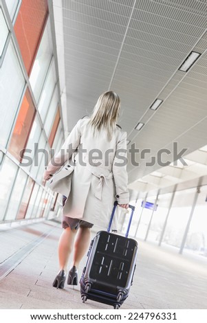 Full length rear view of young businesswoman with luggage walking in railroad station