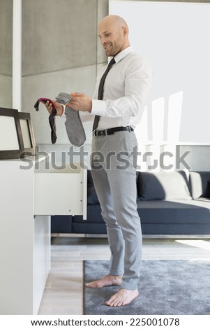 Full length side view of businessman selecting socks at home