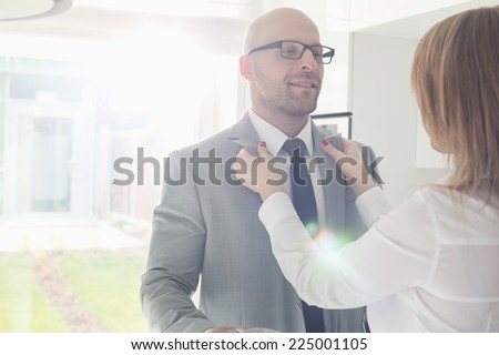 Woman dressing up businessman at home