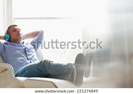 Full-length of relaxed Middle-aged man listening to music at home