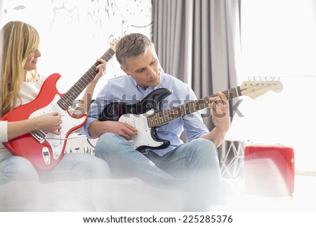 Father and daughter playing electric guitars at home