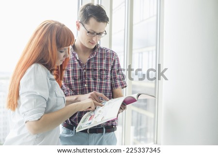 Business colleagues reading file in creative office