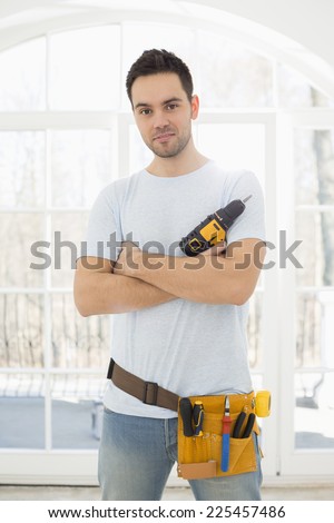 Portrait of confident man with hand drill in new house