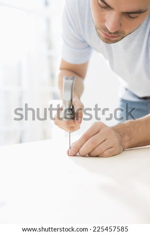 Mid-adult man nailing in table