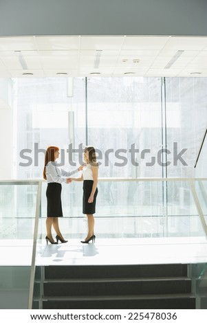 Full-length of businesswomen shaking hands at office hallway