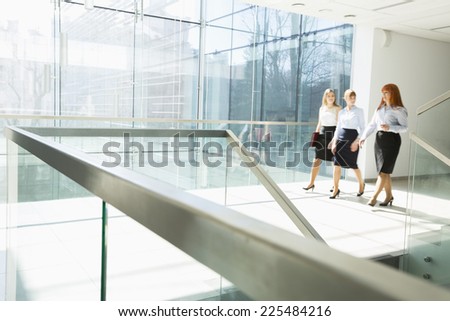 Full-length of businesswomen walking at office hallway