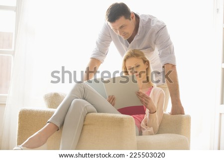 Couple reading magazine together at home