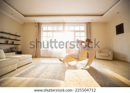 Rear view of man relaxing on modern chair at home