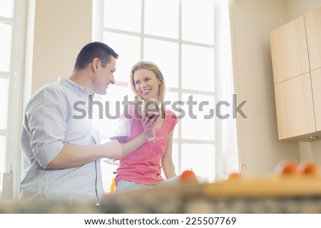 Happy couple drinking red wine in kitchen
