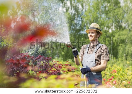 Smiling man watering plants at garden
