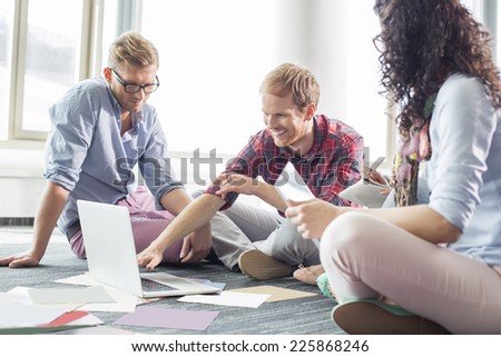 Businessman explaining plan on laptop to colleagues at creative office