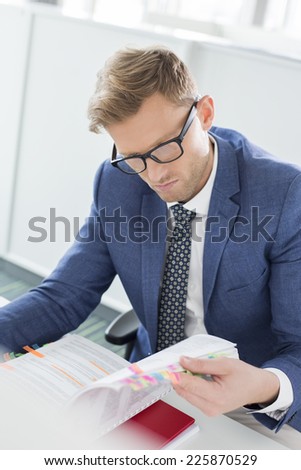 Businessman reading file at desk in creative office