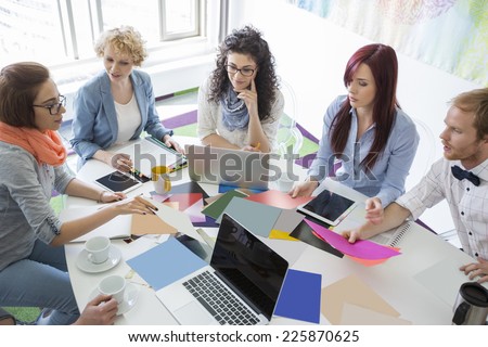 High angle view of businesspeople analyzing photographs in creative office