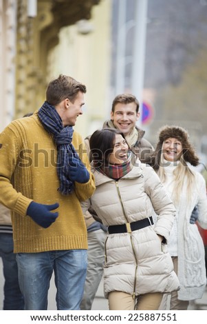 Cheerful young couples in warm clothing on city street