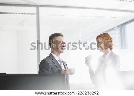 Businessman and businesswoman having coffee in office