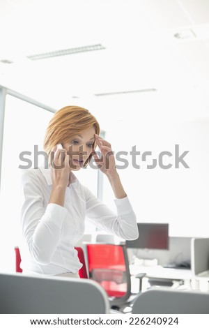 Shock businesswoman using cell phone in office