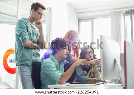 Creative business colleagues discussing over computer in office