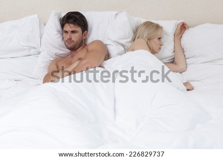 Angry young couple lying in bed