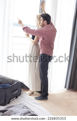 Full length of man showing something to woman at window