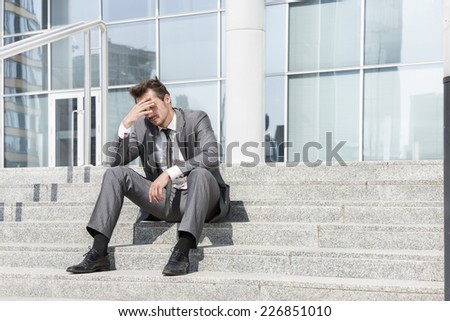 Full length of depressed businessman sitting on steps outside office