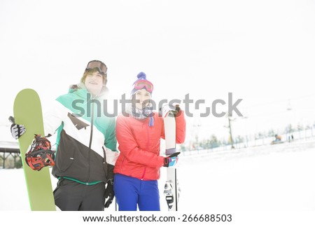 Young couple with snowboard and skis in snow