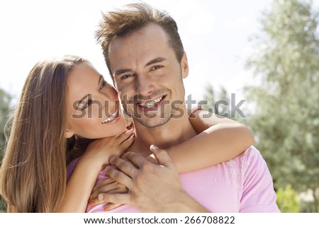 Beautiful young woman embracing man from behind in park