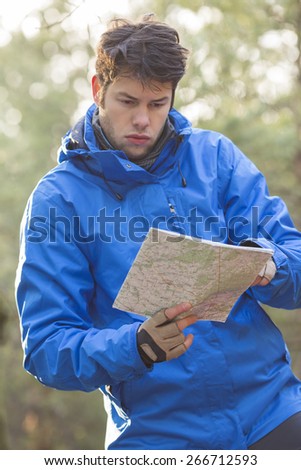 Young male hiker reading map in forest