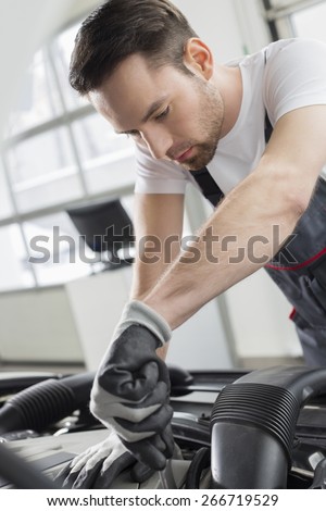 Young maintenance engineer repairing car in automobile store