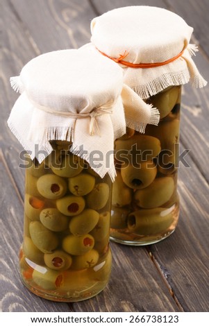 Pickled olives in jar on wooden table