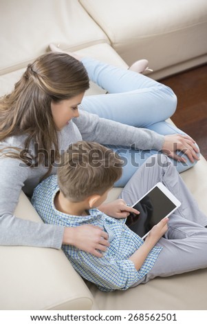 High angle view of mother and son using tablet PC on sofa