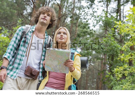 Low angle view of hiking couple with map in forest