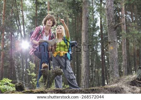Young hiking couple with map discussing over direction in forest