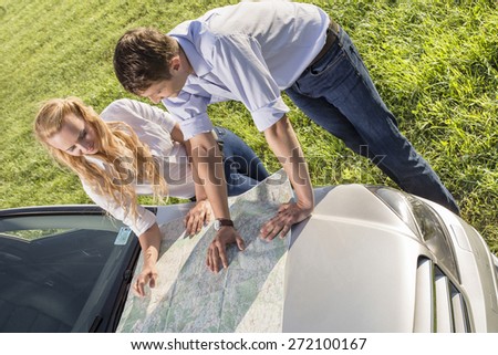 High angle view of couple reading map on car hood during road trip