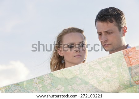 Couple reading map against sky