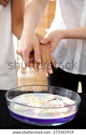 Woman receiving heat therapy on hand over bowl filled with candles