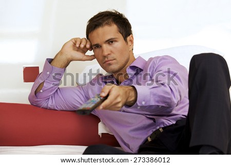 Young man on bed using remote control