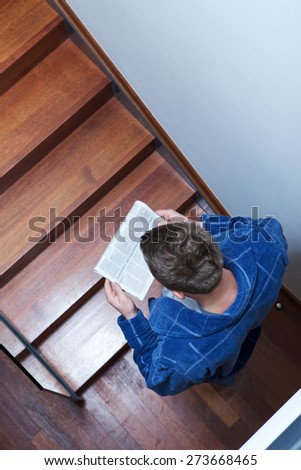 Man reading newspaper on stairs