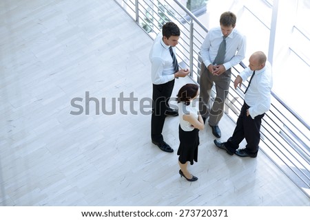 Businessmen and woman standing together by railing and conversing