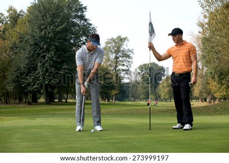 Young man with his friend playing golf in golf course