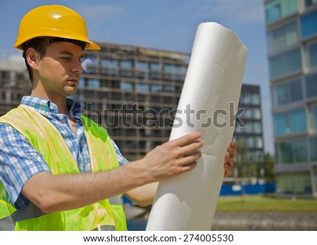 Engineer looking at blueprint on construction site
