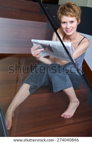 Woman reading newspaper on stairs