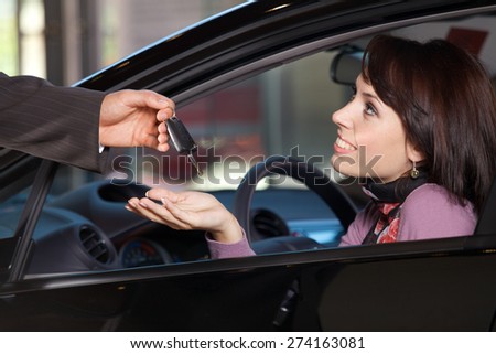 Young woman receiving the car keys from car salesman