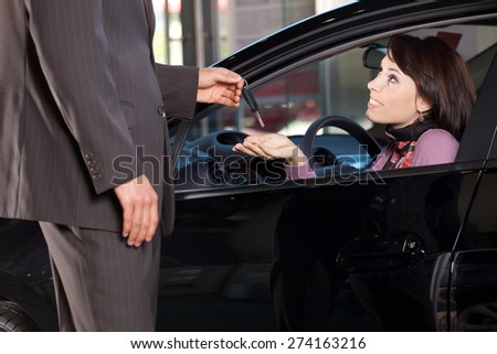 Car salesman giving the car keys to a young woman