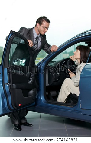 Car salesperson explaining car features to customer