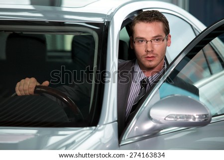 Car salesperson getting in car at showroom