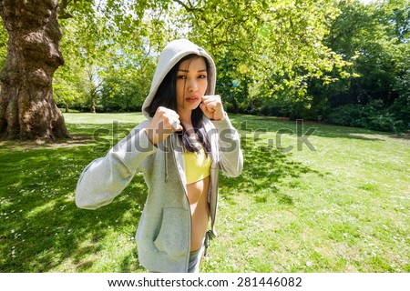 Portrait of determined fit woman practicing boxing at park