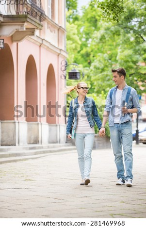 Full length of young college couple talking while walking in campus