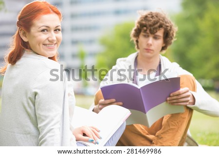 Portrait of happy young woman with male friend studying at college campus
